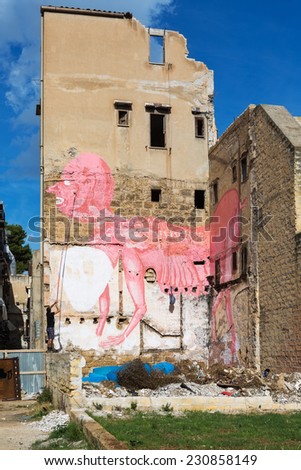PALERMO, ITALY - OCTOBER 23, 2014: Man paining image of a pink monster on the ruined walls of the house in Palermo city center. Palermo has reputation of one of dirtiest cities in Italy.