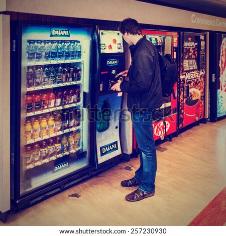 VANCOUVER, CANADA  - MAY 22, 2007: Unidentified male student paying for drinks from the vending machine at Simon Fraser University Convenience Centre. Postprocessed in vintage retro instagram style.