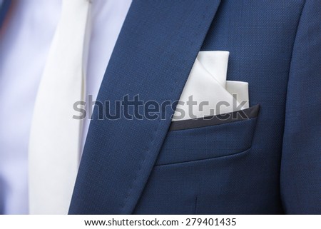 Elegant blue stylish jacket with handkerchief peeking out of the pocket and with white tie; a wedding suit.