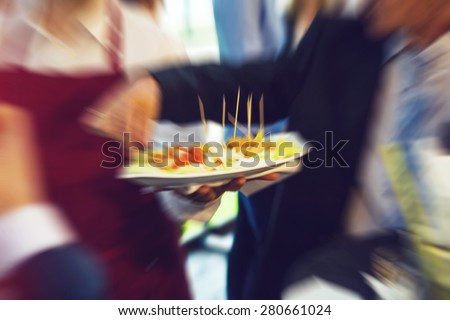 Waiter serving food on a plate during wedding evening, defocused with radial zoom blur, vintage retro instagram effect added