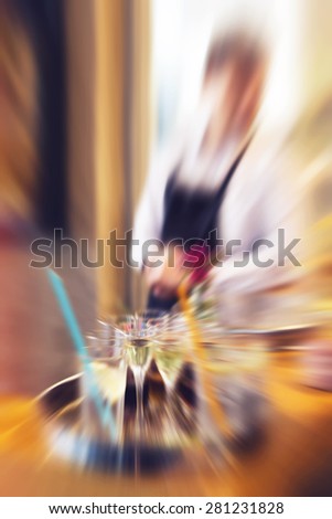 Waiter serving drinks on a tray during wedding evening, defocused with radial zoom blur, vintage retro instagram effect added