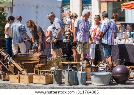 L'ISLE-SUR-LA-SORGUE, FRANCE - AUGUST 14, 2015: Old garden equipment on street antique shop stand on flea market. Town is famous for its many antique shops and hosts antique markets most Sundays.