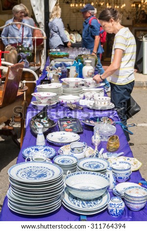 L\'ISLE-SUR-LA-SORGUE, FRANCE - AUGUST 14, 2015: Old serving plates on street antique shop stand on flea market. Town is famous for many antique shops and hosts antique markets most Sundays.