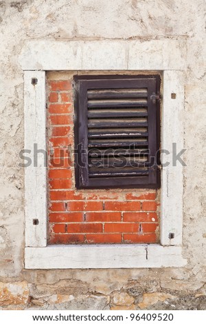 Wooden window inside a larger concrete window with bricks inside to fill the gap