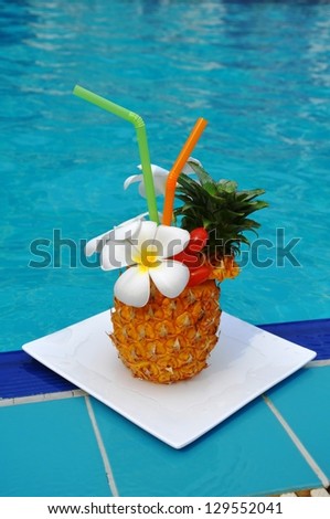 Tropical pineapple cocktail. Drink on the background of the pool.