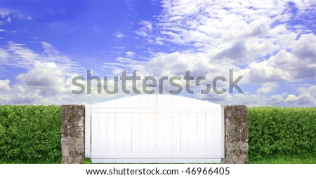 White  wood and stone gate  with green hedges and blue sky