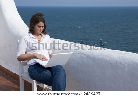 Young woman with a mac laptop in a mediterranean look terrace near the ocean