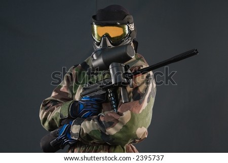 Paintball player with gun, wearing protective mask and cloth