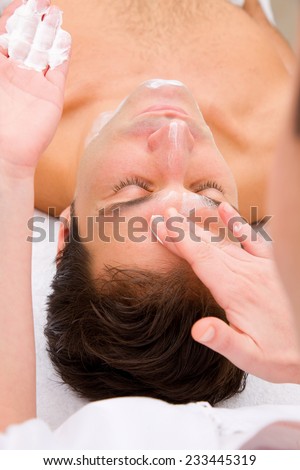 Beautician applying moisturizer man\'s face