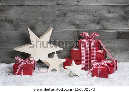 Red Christmas gifts with wooden starts on grey wooden background.