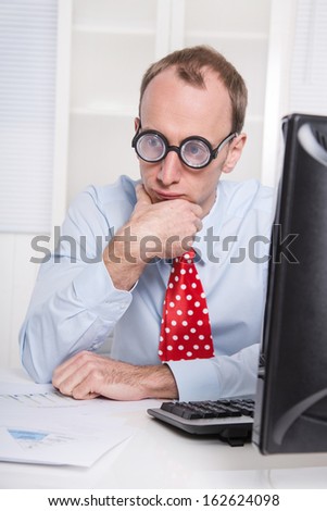 Overworked businessman with glasses staring into space at desk - stress and burnout