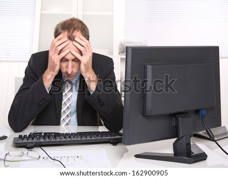 Overworked businessman frustrated and stressed in his office with computer - overtime.