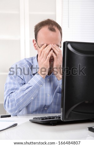 Overworked businessman frustrated and stressed in his office with computer - overtime.