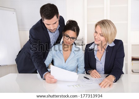 Teamwork between three business people at desk at office.