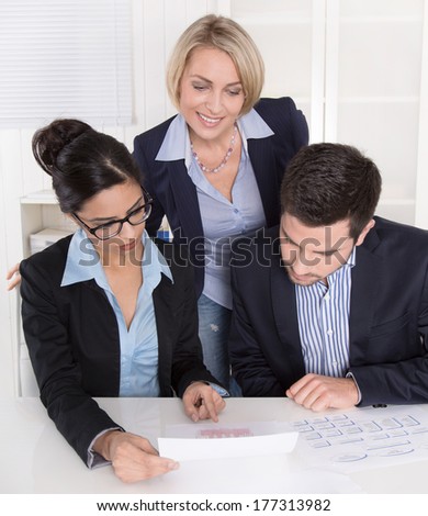 Teamwork between three business people at desk at office.
