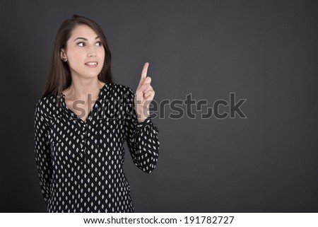 Pretty mixed race woman isolated over black board pointing with finger.