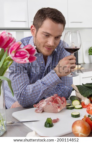Single man in his kitchen after work drinking a glass of red wine.