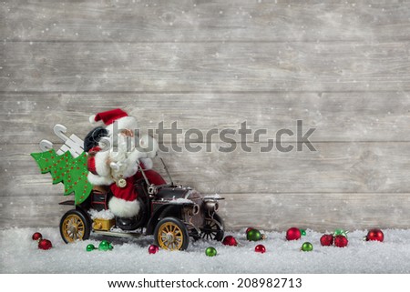 Santa claus in rush with his car: christmas shopping stress. Decoration with old vintage tin toys on wooden background.