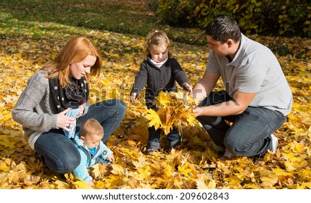 Happy young family in fall making a walk and play with maple leaves.