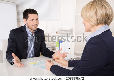 Job interview or meeting situation: business man and woman at desk.