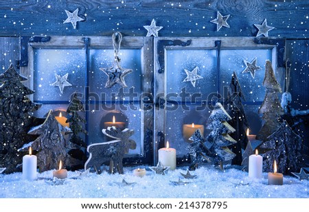 Outdoor christmas window decoration in blue with wood and candles.