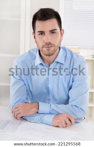 Portrait of a successful businessman in blue shirt sitting in his office.