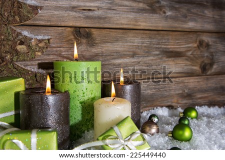 Four burning apple green christmas candles on wooden background.