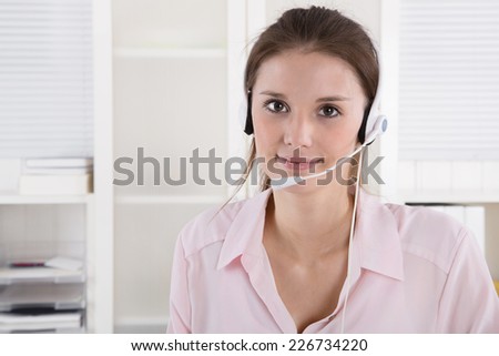 Pretty young business woman in rose blouse with headset.