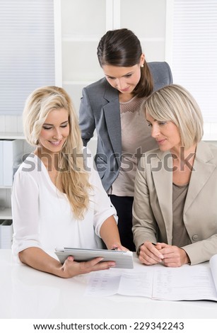Successful team of female business people looking at tablet computer for a presentation.
