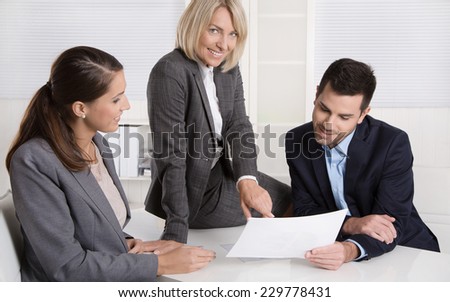 Successful teamwork: career businesswoman and businessman sitting around a table talking together in a meeting.