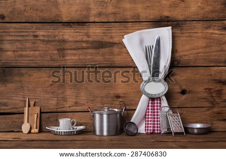 Invitation for a dinner. Red white checked cutlery on old wooden background with tableware.