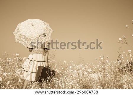 Nostalgic old photo in sepia color. Girl with her umbrella walking alone and searching her way.