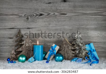 Blue, white and grey Christmas decoration with one burning candle for the first advent.