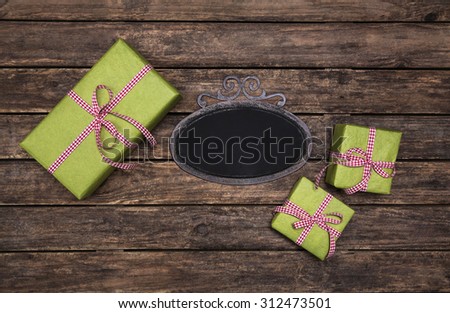 Old wooden dark brown background with apple green red white checked gift boxes for christmas.