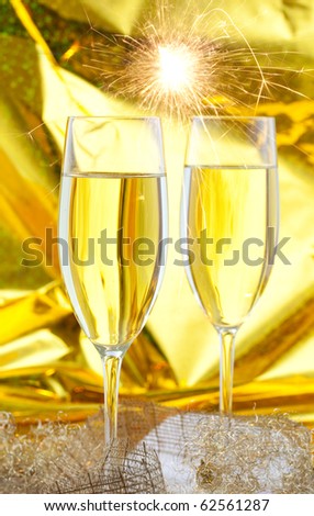 two filled sparkling wine glasses in front of golden background