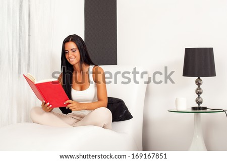 Beautiful woman sitting on the sofa and  reading a book. Selective focus on face.
