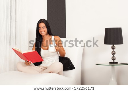 Beautiful woman sitting on the sofa and reading a book