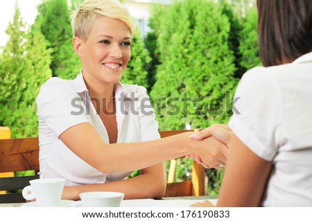 Two women face to face at a business meeting handshaking