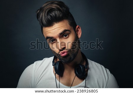 Handsome DJ posing in studio on dark background with headphones