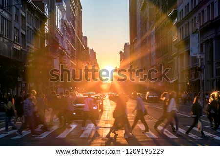 Sunlight shines over the buildings and people of a busy Midtown Manhattan street scene in New York City NYC