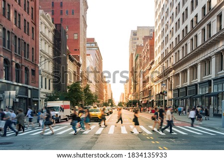 Crowds of people walking through a busy crosswalk at the intersection of 23rd Street and Fifth Avenue in Midtown Manhattan, New York City NYC