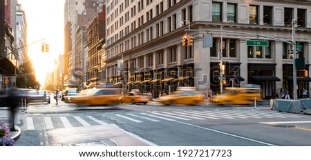 Yellow taxis driving through the busy intersection of 5th Avenue and 23rd Street in Manhattan, New York City USA
