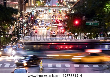 Buses and taxis driving through a busy intersection 42nd Street through Midtown Manhattan in New York City at night 