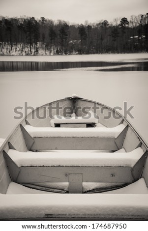 Row boat covered in the snow on frozen lake