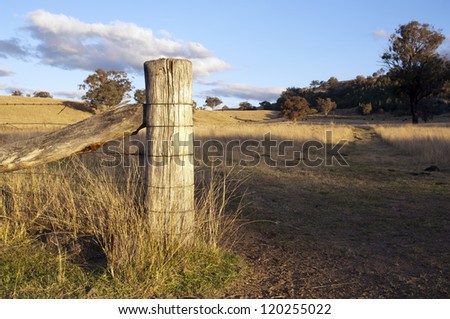 Farm fence at gate opening with paddock behind in rural Australia