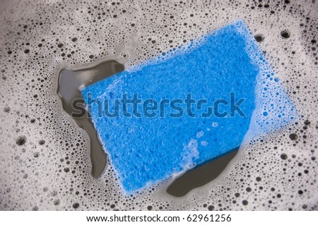 Blue sponge and dirty dish water in a sink