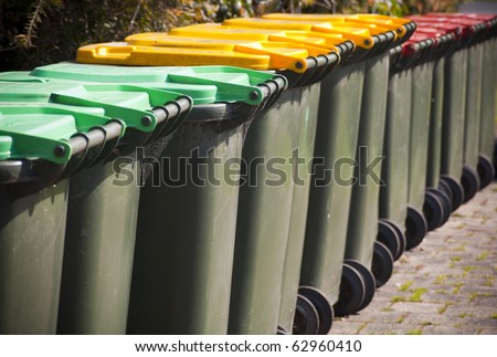 Row of large green wheelie bins for rubbish, recycling and garden waste