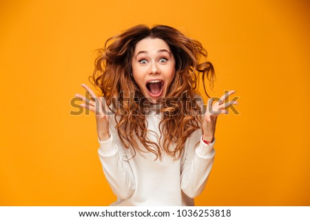 Photo of Image of excited screaming young woman standing isolated over yellow background. Looking camera.
