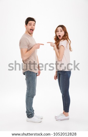 Full length photo of amazing adult guy and girl wearing beige t-shirts posing together on camera standing face to face and pointing fingers to each other over white background ストックフォト © 