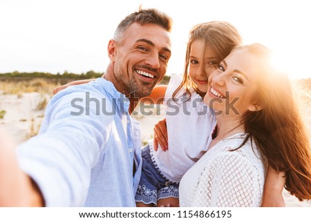 Photo of Happy family spending good time at the beach together, taking selfie
